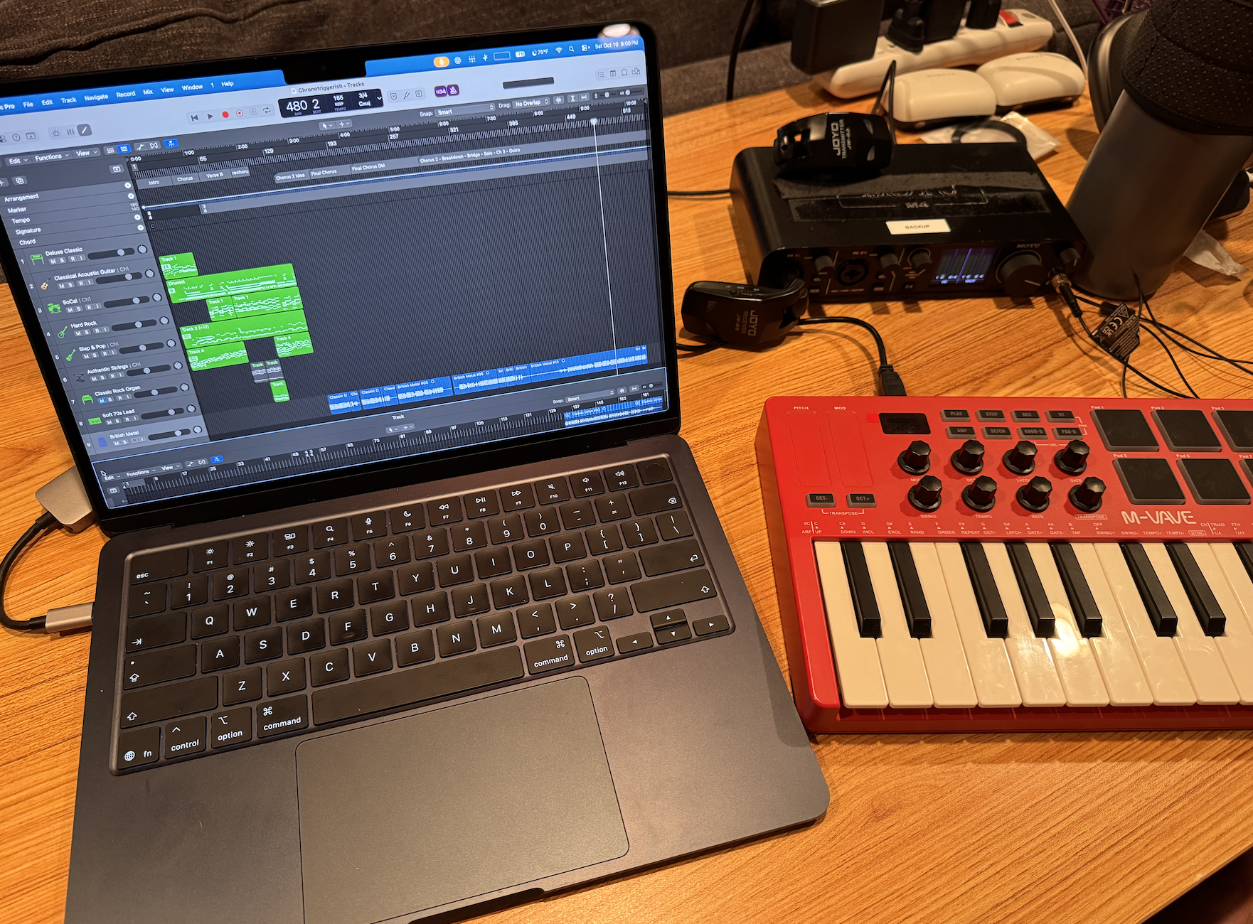 A laptop, audio interface, and small musical keyboard on a desk